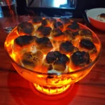 AI Lava Mukbang Recipe: The Ultimate Viral Dessert Explosion 5 Charred marshmallows glowing over a fiery orange base in a glass bowl for the AI Lava Mukbang Recipe.