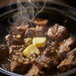 Close-up of juicy steak bites slow-cooked in crockpot with parsley and melted butter