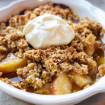 Freshly baked apple crisp recipe without oats with cinnamon-spiced apples and whipped cream topping