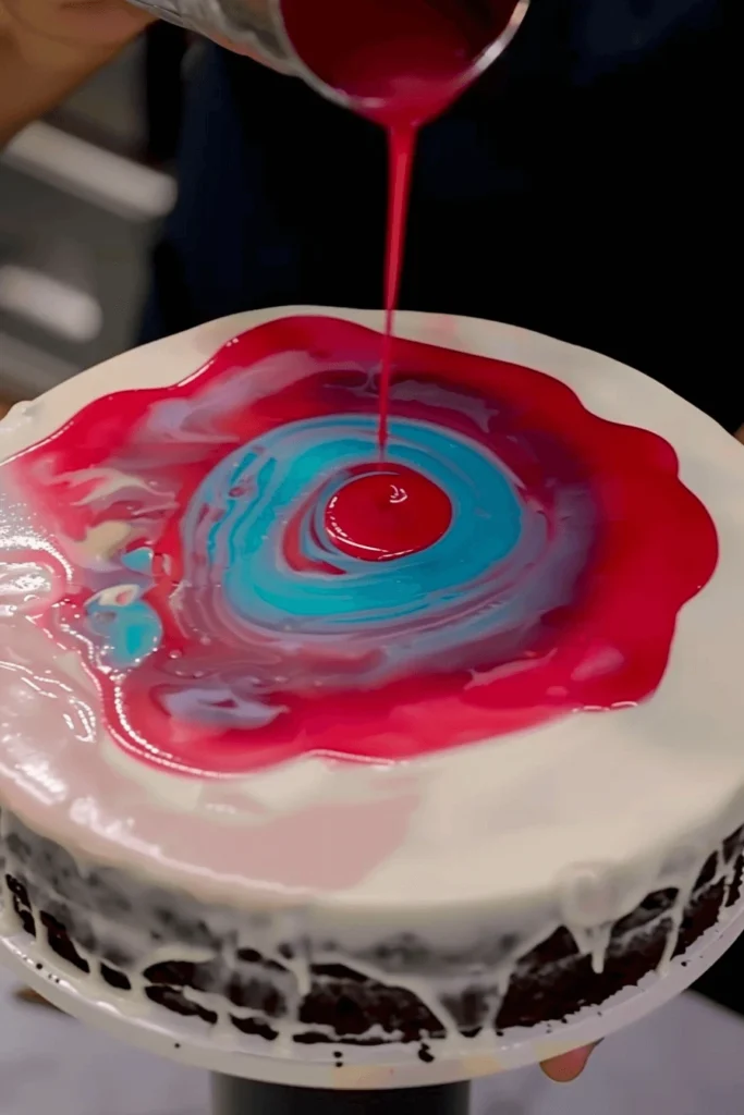 pouring red mirror glaze over chocolate cake