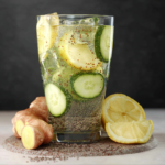 Refreshing glass of ginger cucumber lemon water with cucumber slices, lemon wedges, and ginger root