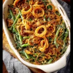 Homemade green bean casserole topped with crispy onions in a rustic dish