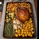 Sheet pan Thanksgiving dinner with roasted turkey, vegetables, and stuffing.