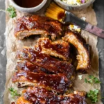 Tender slow cooker ribs glazed with barbecue sauce on a rustic platter.
