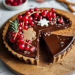 Slice of vegan gingerbread chocolate tart topped with coconut cream.