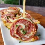 Golden baked salami pinwheels on a parchment-lined baking sheet