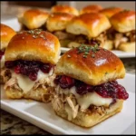 Turkey cranberry sliders served on a wooden board with melted cheese