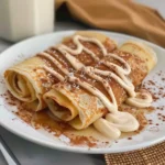 Cinnamon roll protein crepes stacked with cinnamon drizzle