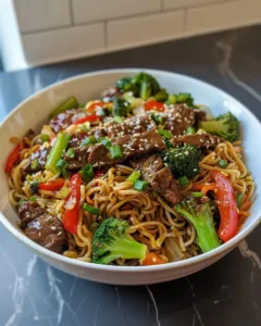 Delicious Sticky Beef Noodles served in a bowl with fresh herbs and vegetables